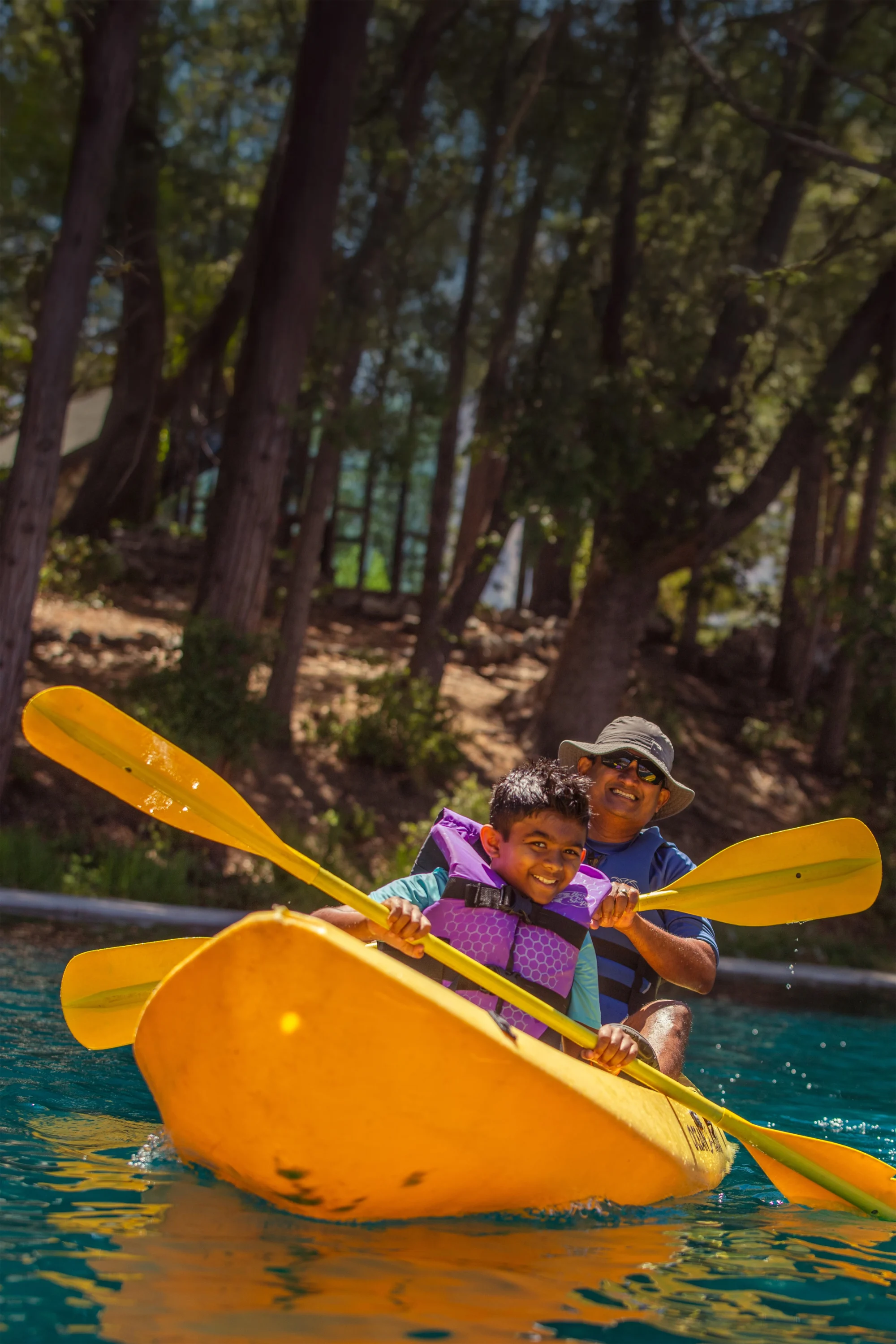 dad and son smiling in a kayak at family camp
