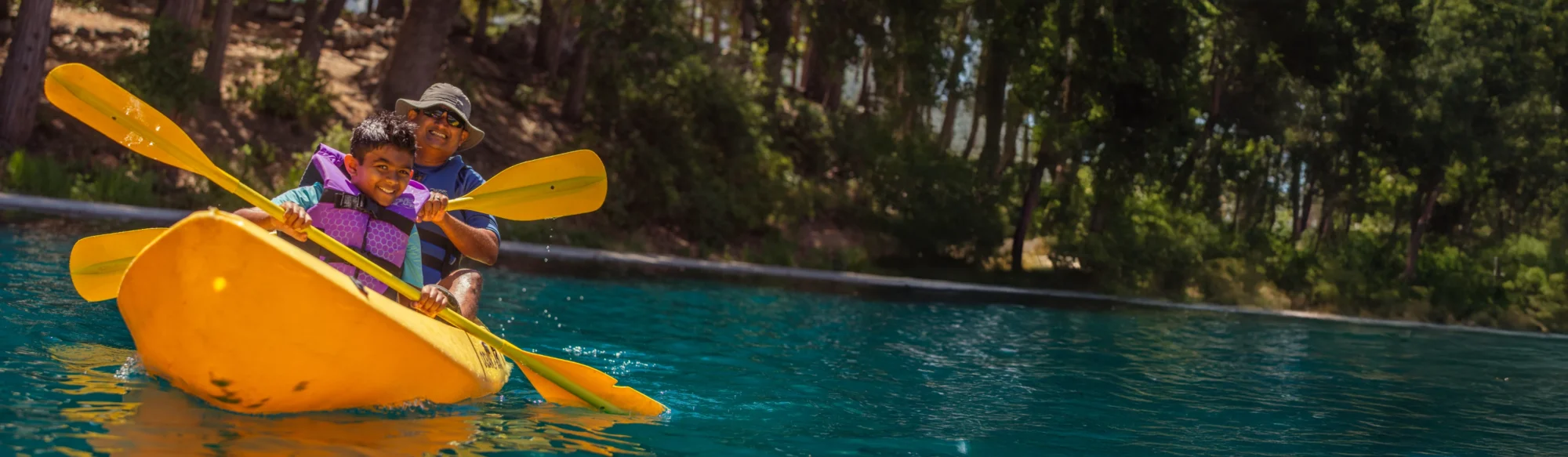 dad and son smiling in a kayak at family camp