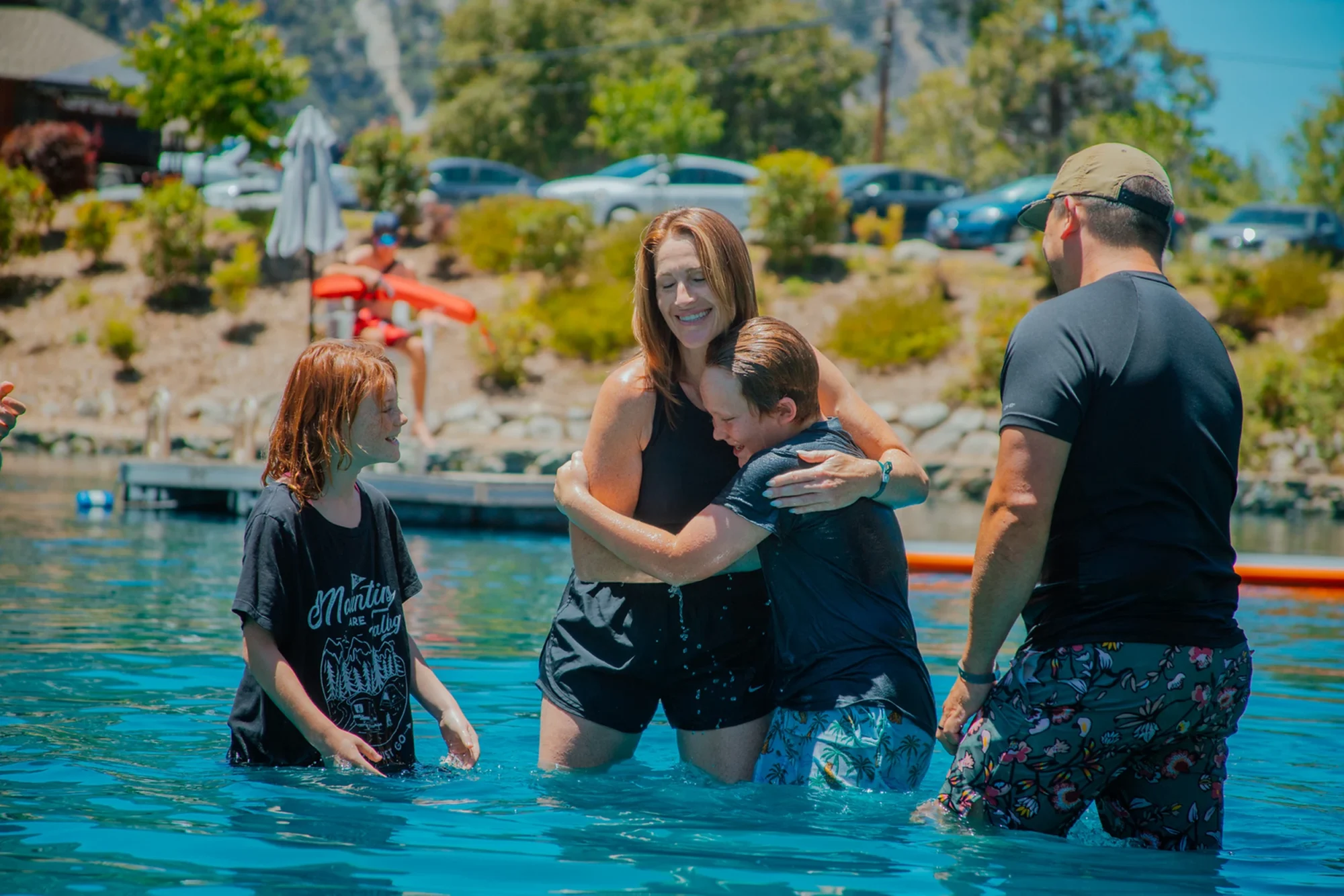 family camp baptism family embracing son after lake immersion
