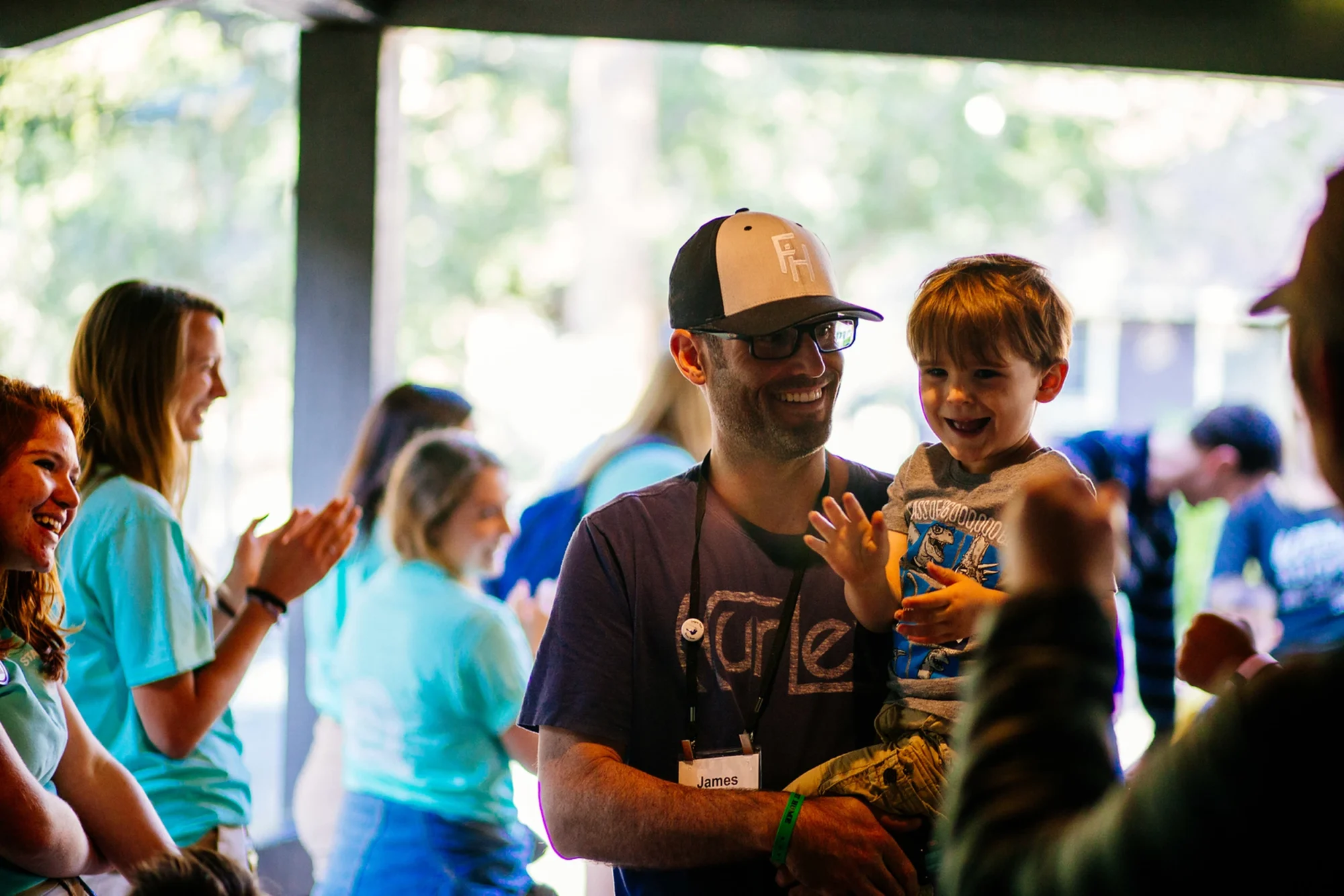 family camp dad glasses holding toddler son smiling
