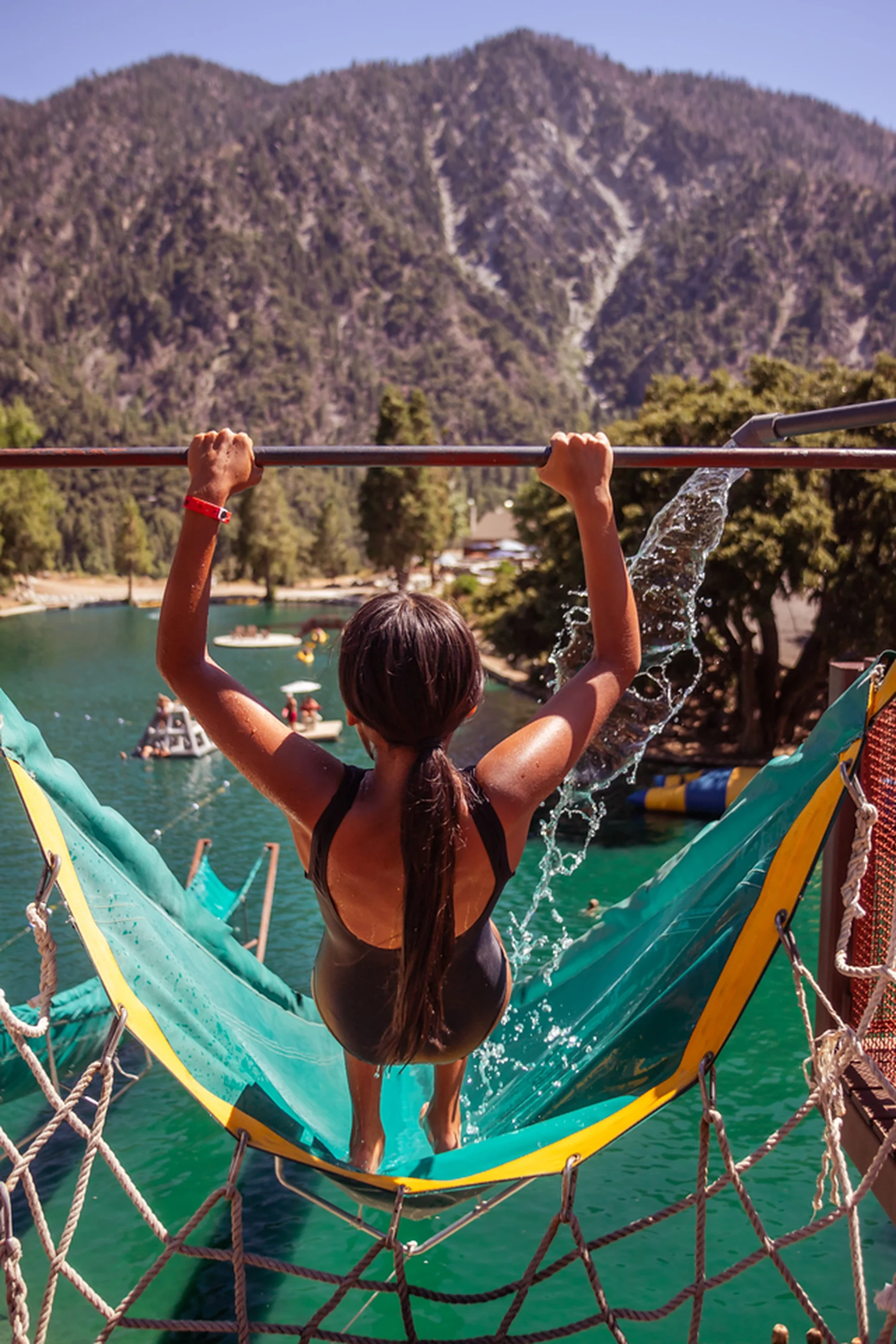 family camp giant water slide girl arms raised mountain lake