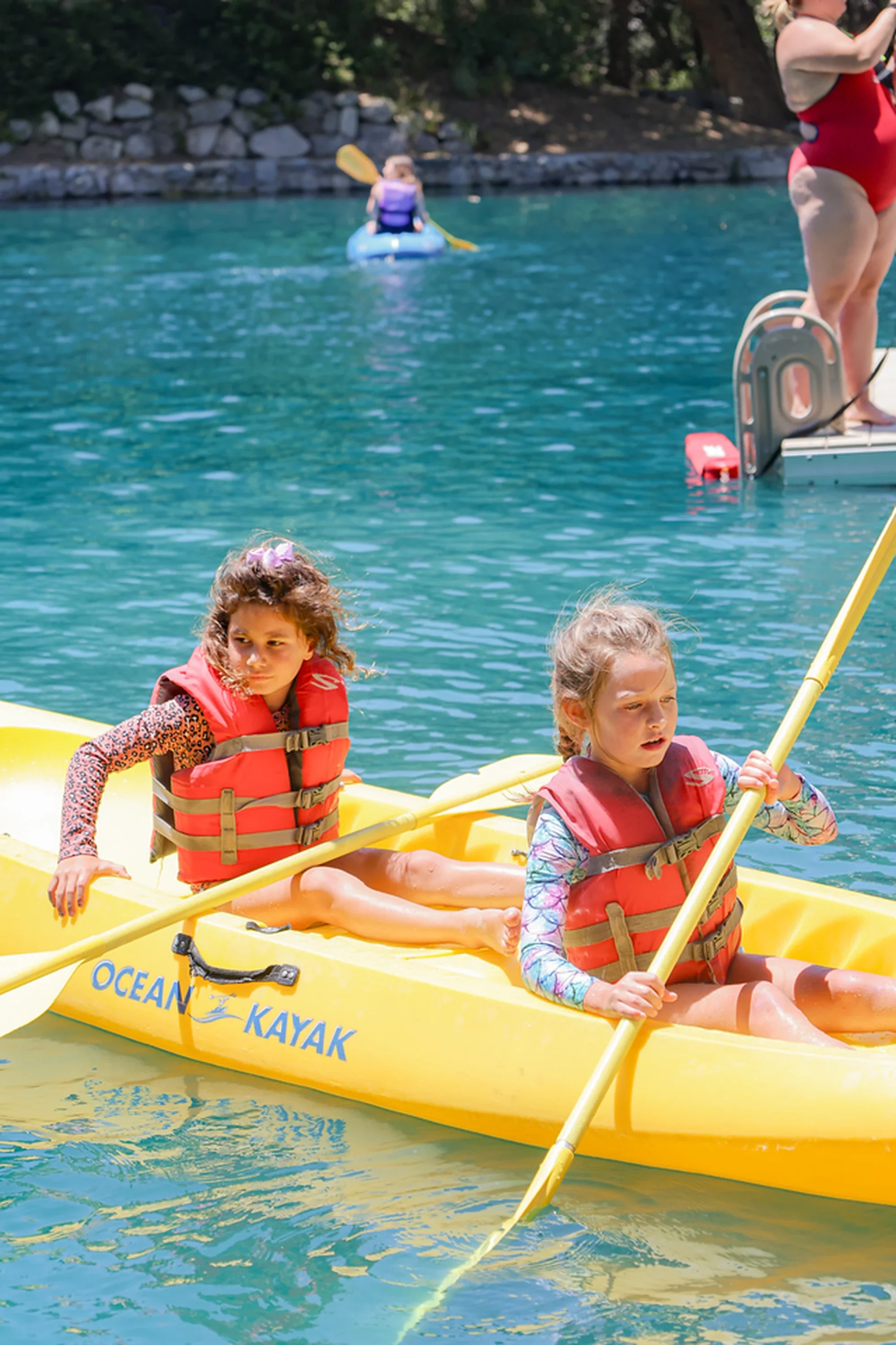 family camp kayak two girls paddling turquoise lake