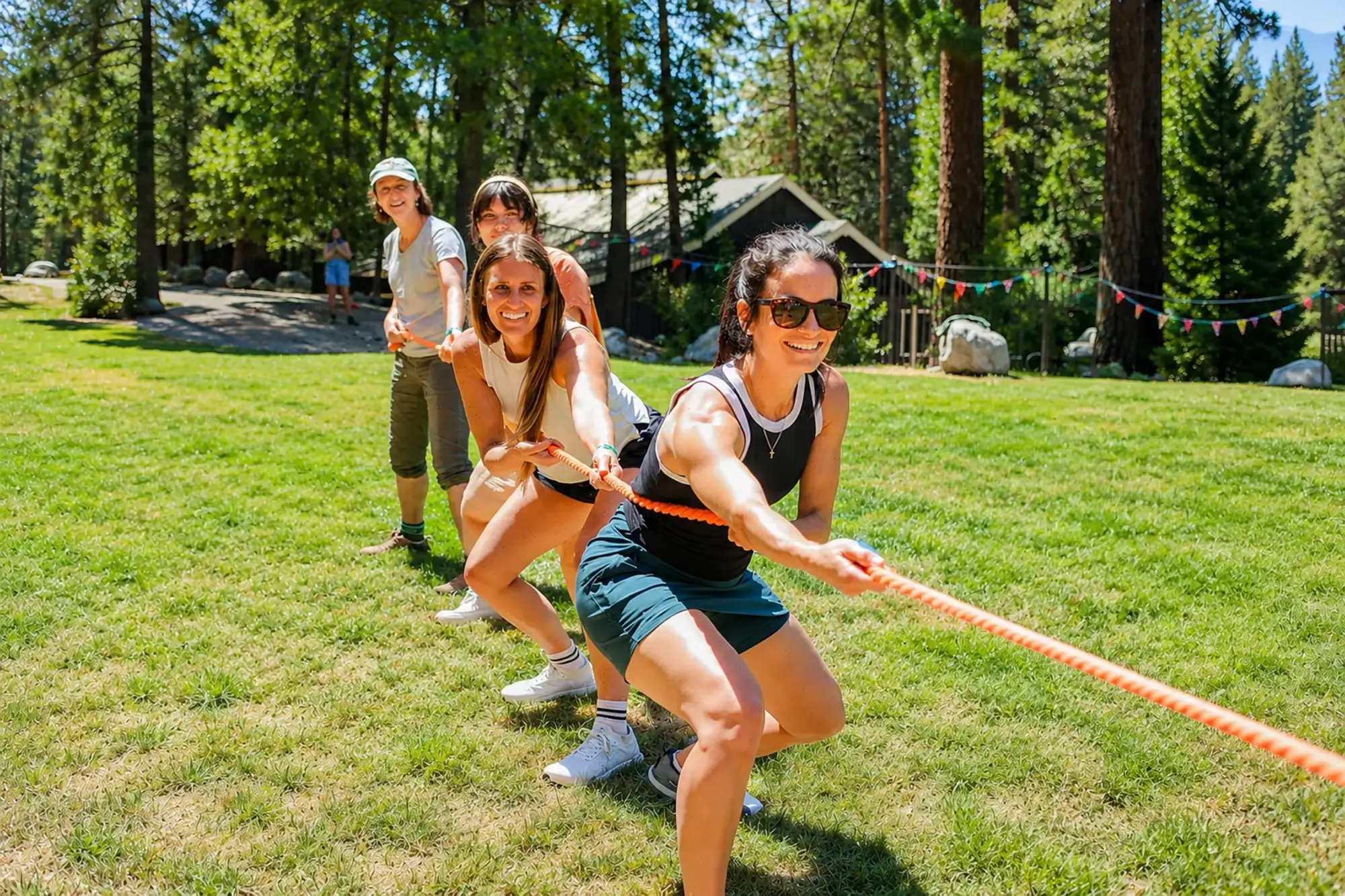 family camp women playing tug of war outdoors fun e1