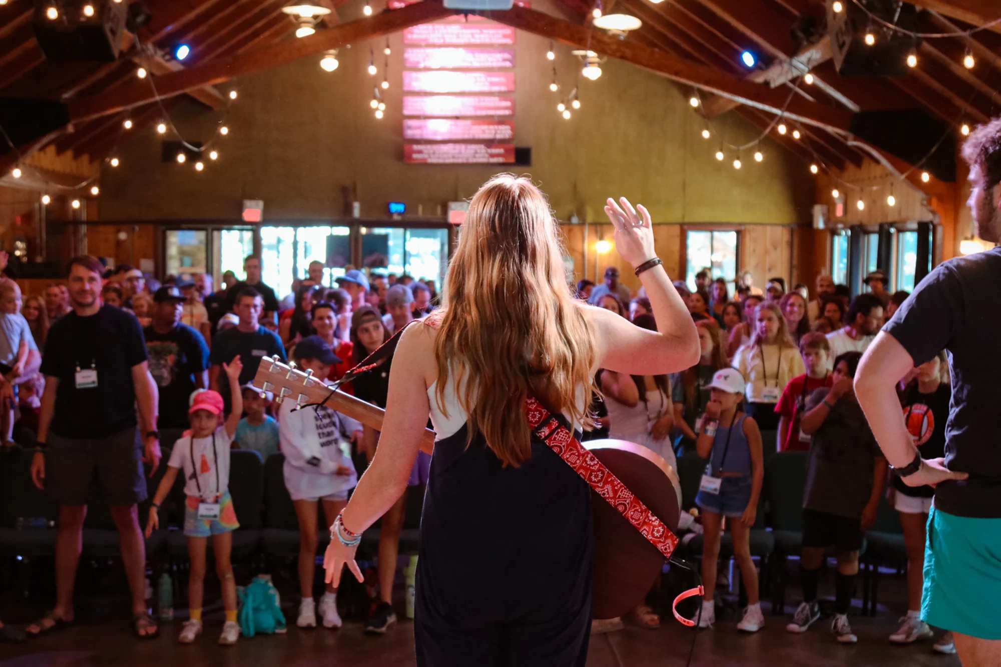 family camp worship leader woman guitar crowd standing rustic venue