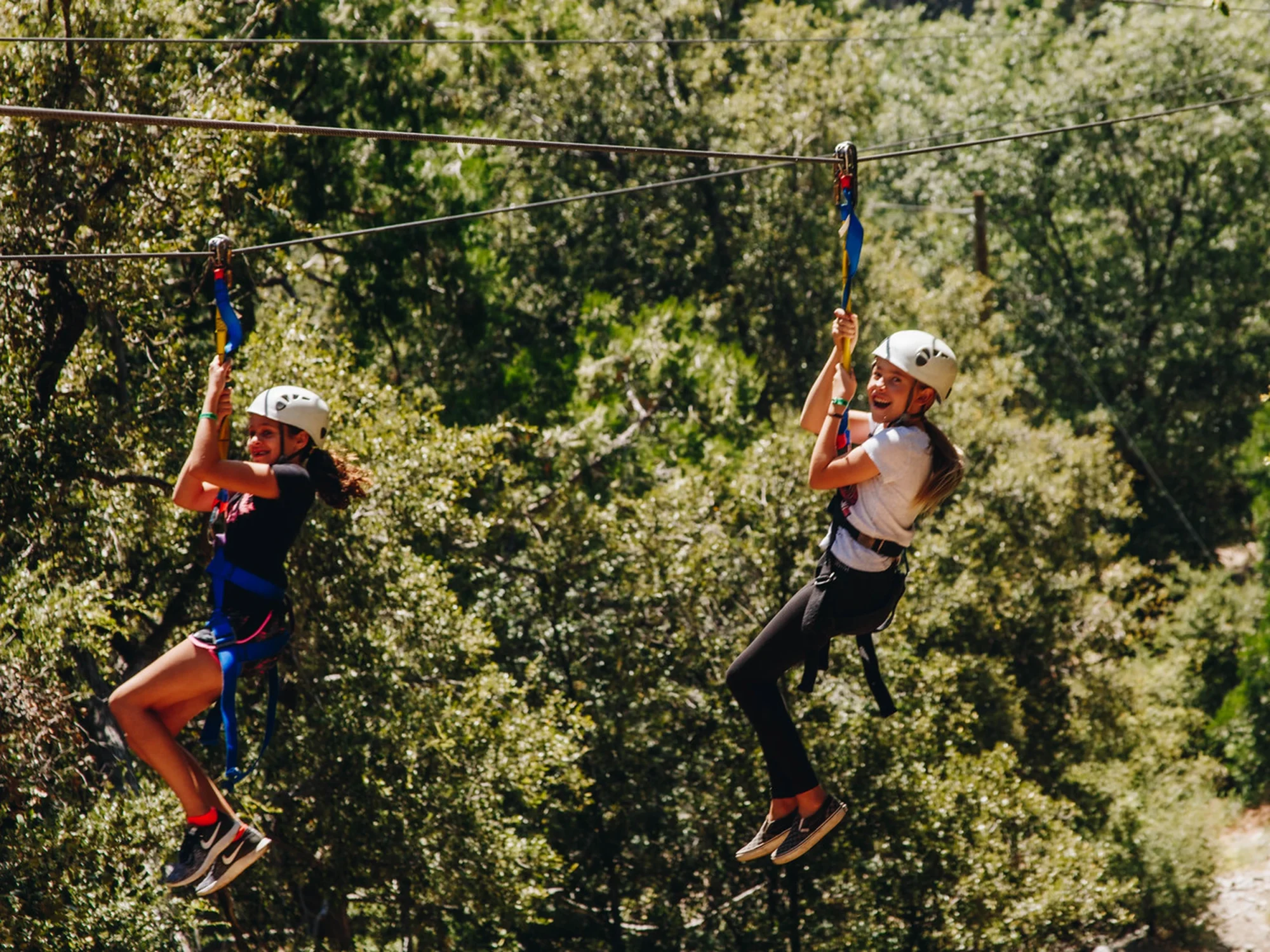 family camp zipline two girls riding together smiling