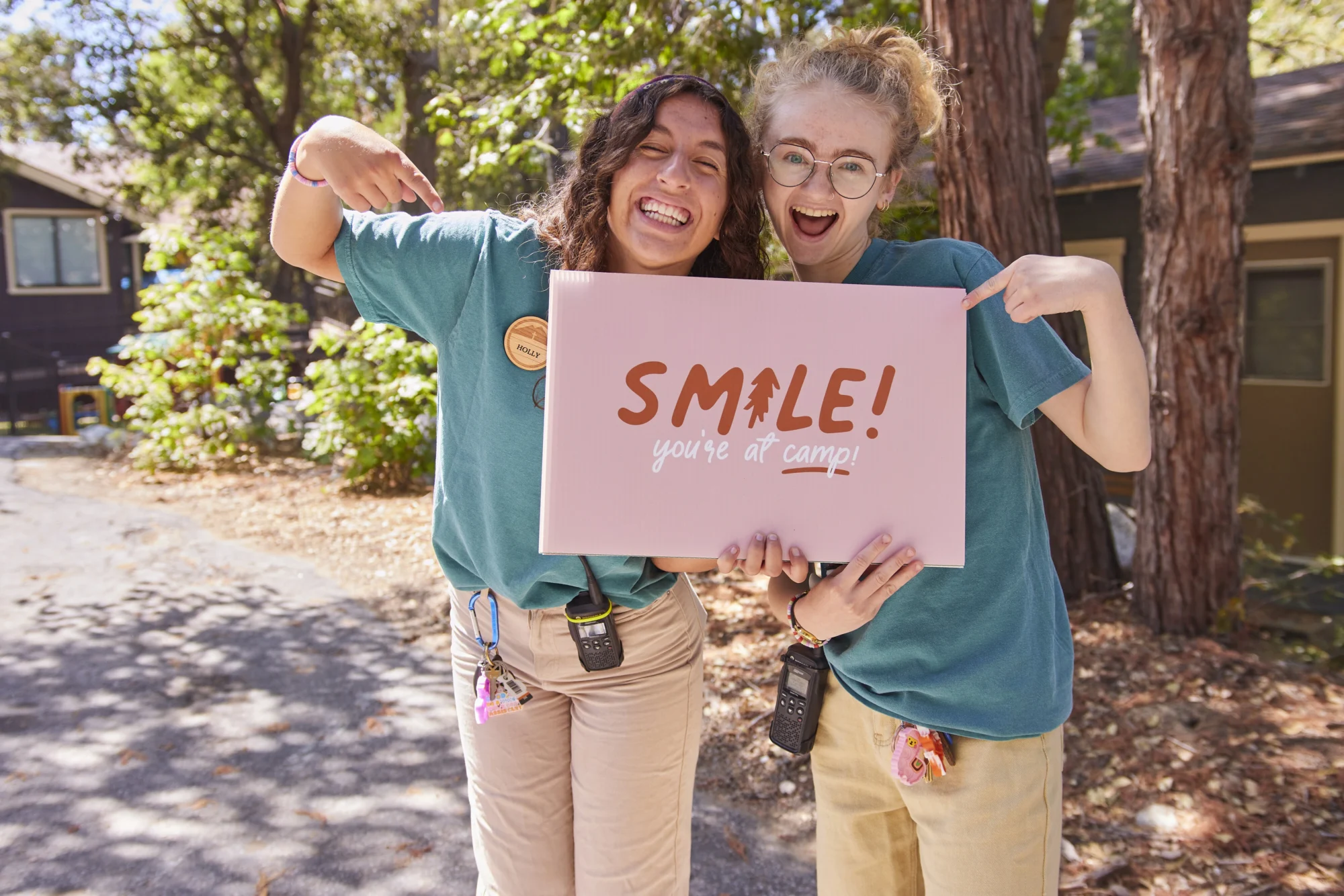 summer staff two staff women holding smile at camp sign