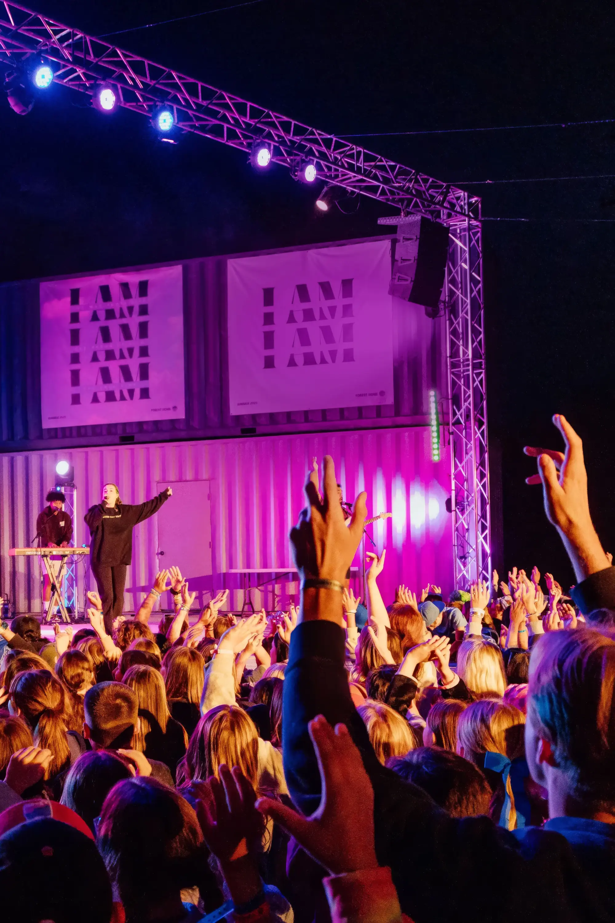 summer youth camp worship speaker stage crowd hands raise tall e1