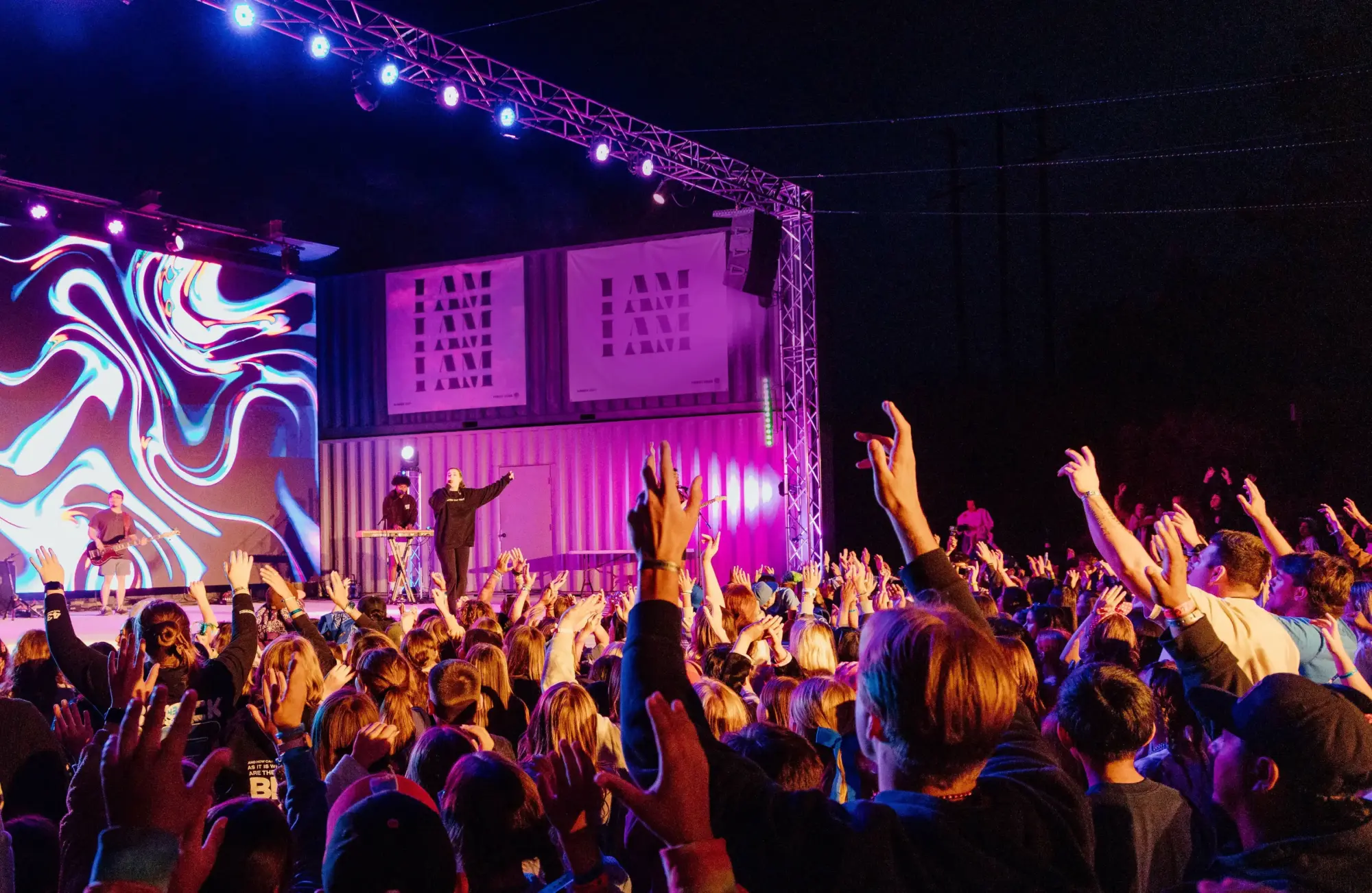 summer youth camp worship speaker stage crowd hands raised e1