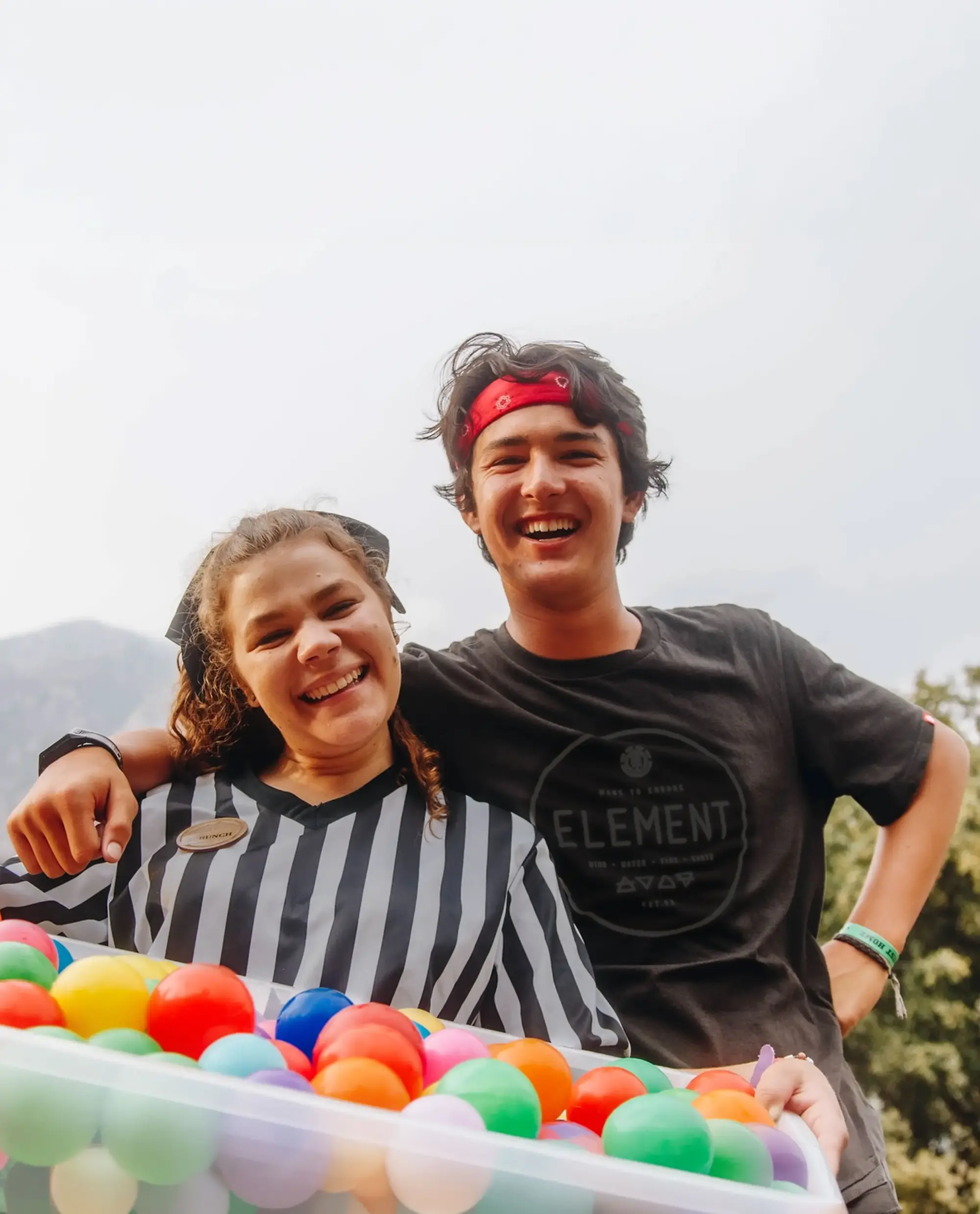 two staff members smiling colorful ball pit mountains tall e1