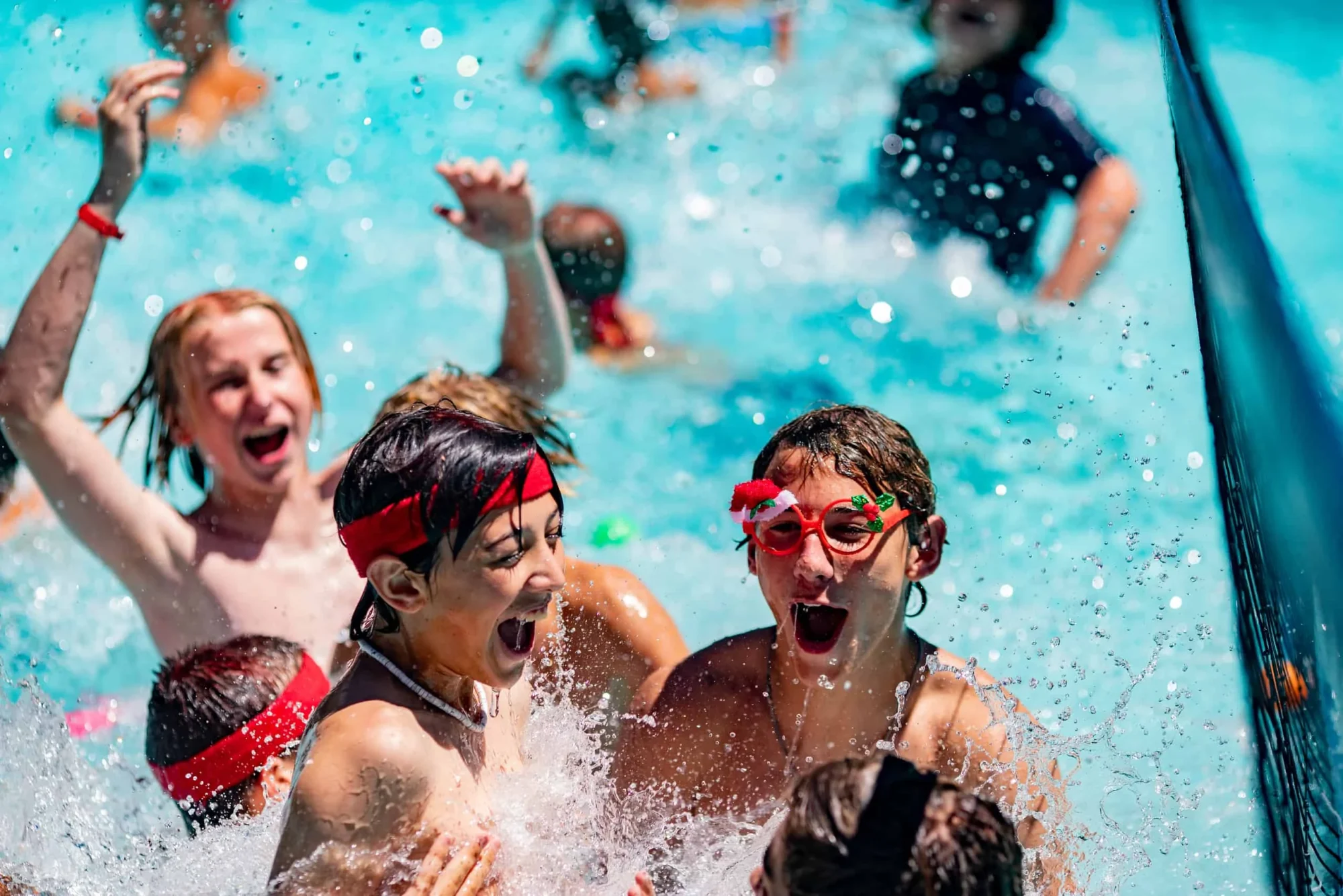 youth campers splashing pool water slide summer fun
